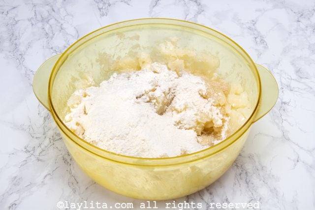 Sobre o purê de mandioca, coloque a farinha de trigo peneirada, o açúcar, a essência de anis e a pitada de sal. Amasse até obter uma massa modelável.