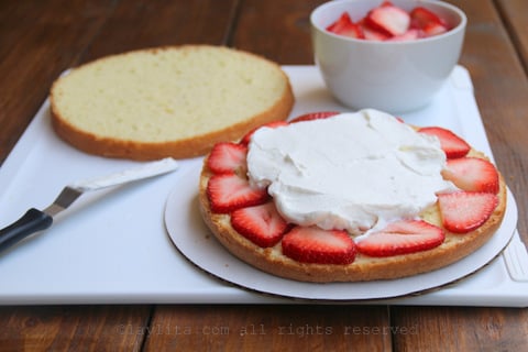 Para montar el pastel, agregue las fresas encima de la primera capa de bizcocho, y agregue la crema batida