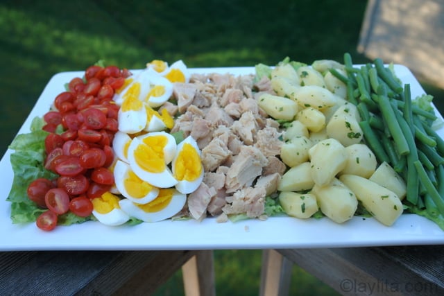 Poner los tomates, huevos duros, atun, papas y vainitas encima de la lechuga