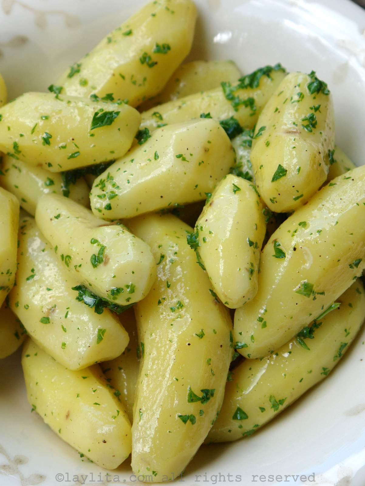Papas pequeñas peladas y cocidas con aderezo de mantequilla y perejil