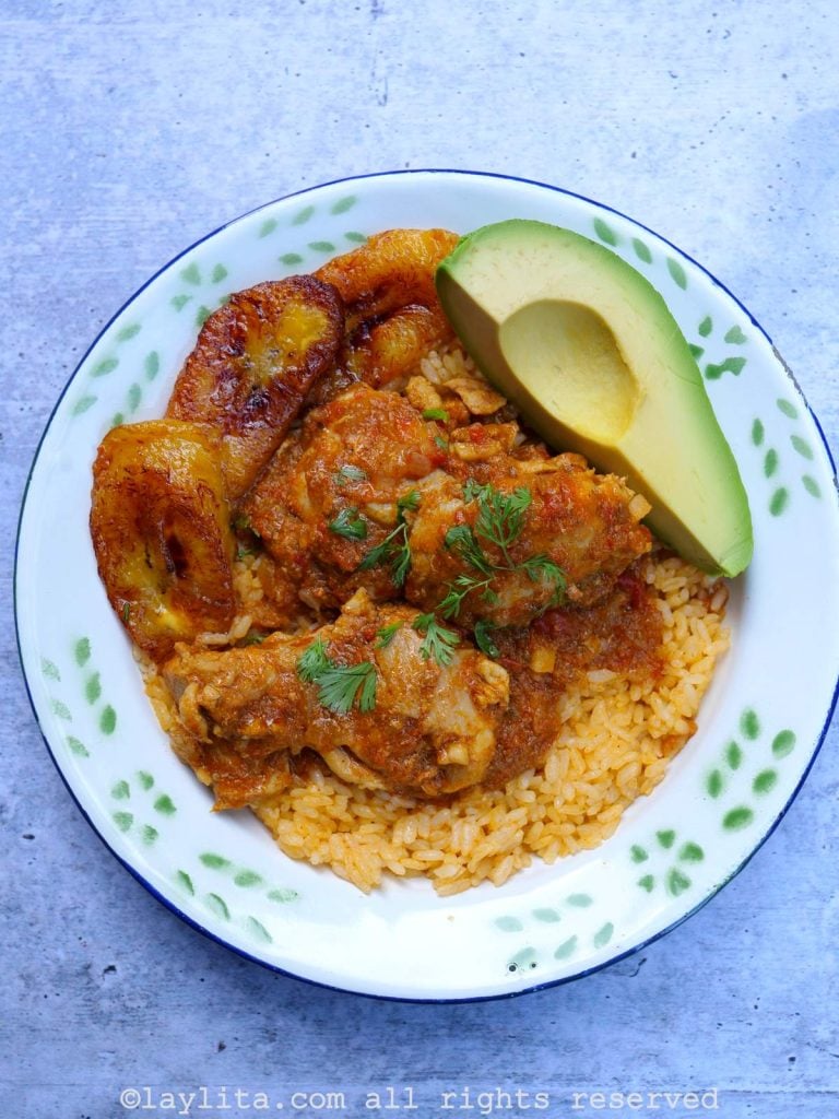 Seco de pollo con arroz amarillo, aguacate y plátanos fritos