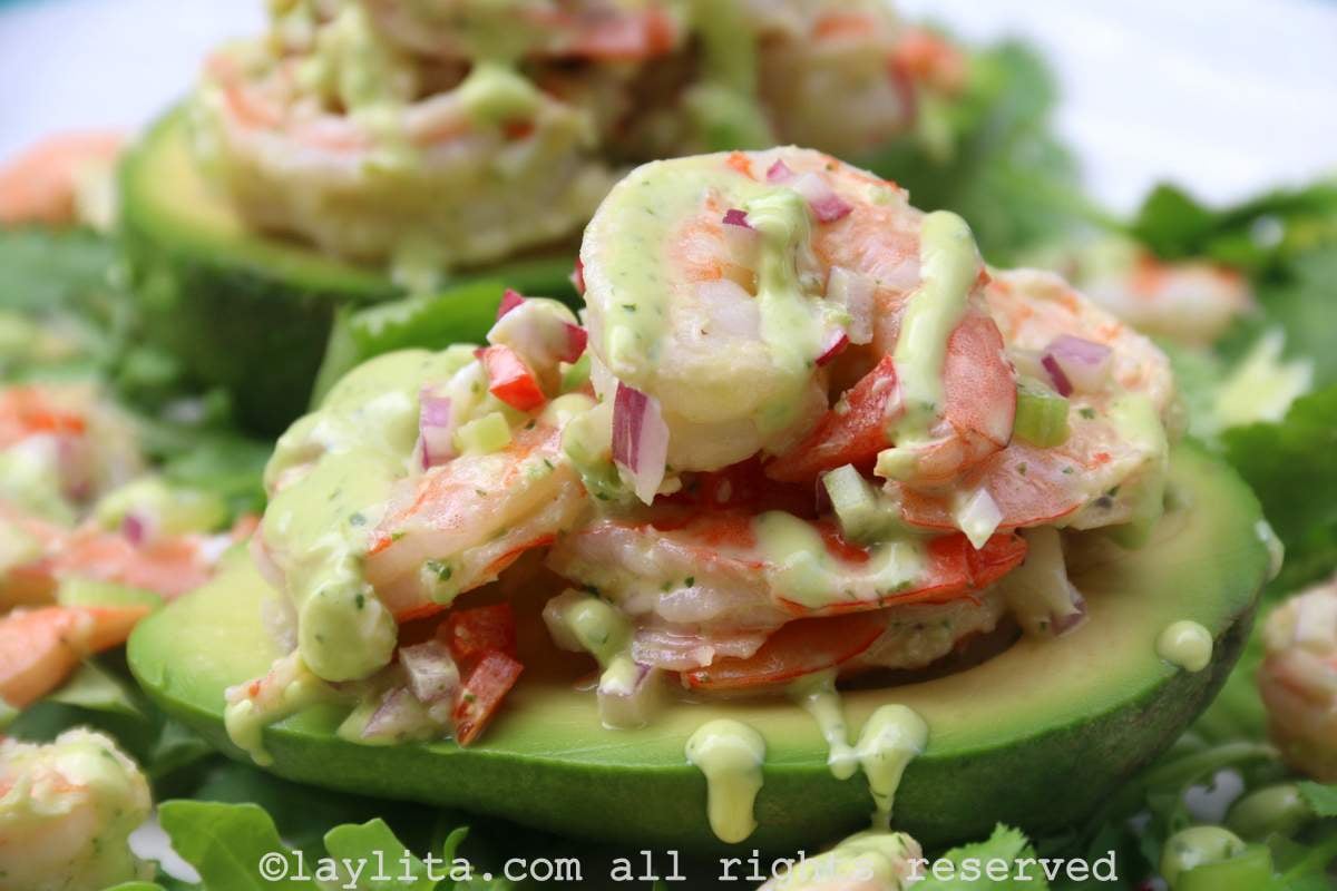 Primer plano de una mitad de aguacate con relleno de ensalada de camarones y mayonesa de cilantro encima