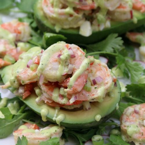 Dos aguacates rellenos con ensalada de camarón en un plato blanco