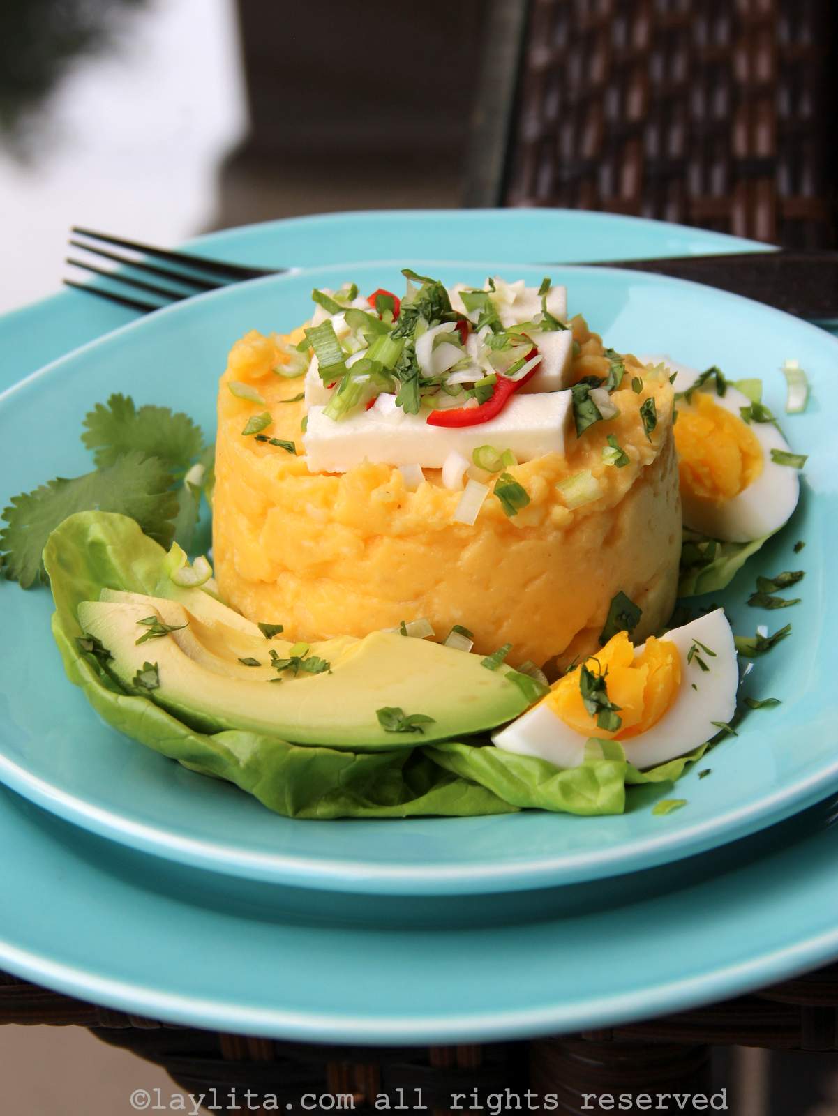 Puré de papas ecuatoriano o molo decorado con aguacate y huevo duro en un plato celeste