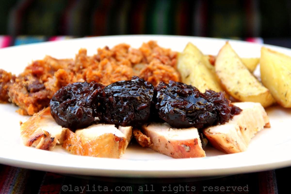 Un plato con trozos de pavo asado con salsa de ciruelas encima, en el fondo del plato hay papas asadas y relleno de pavo