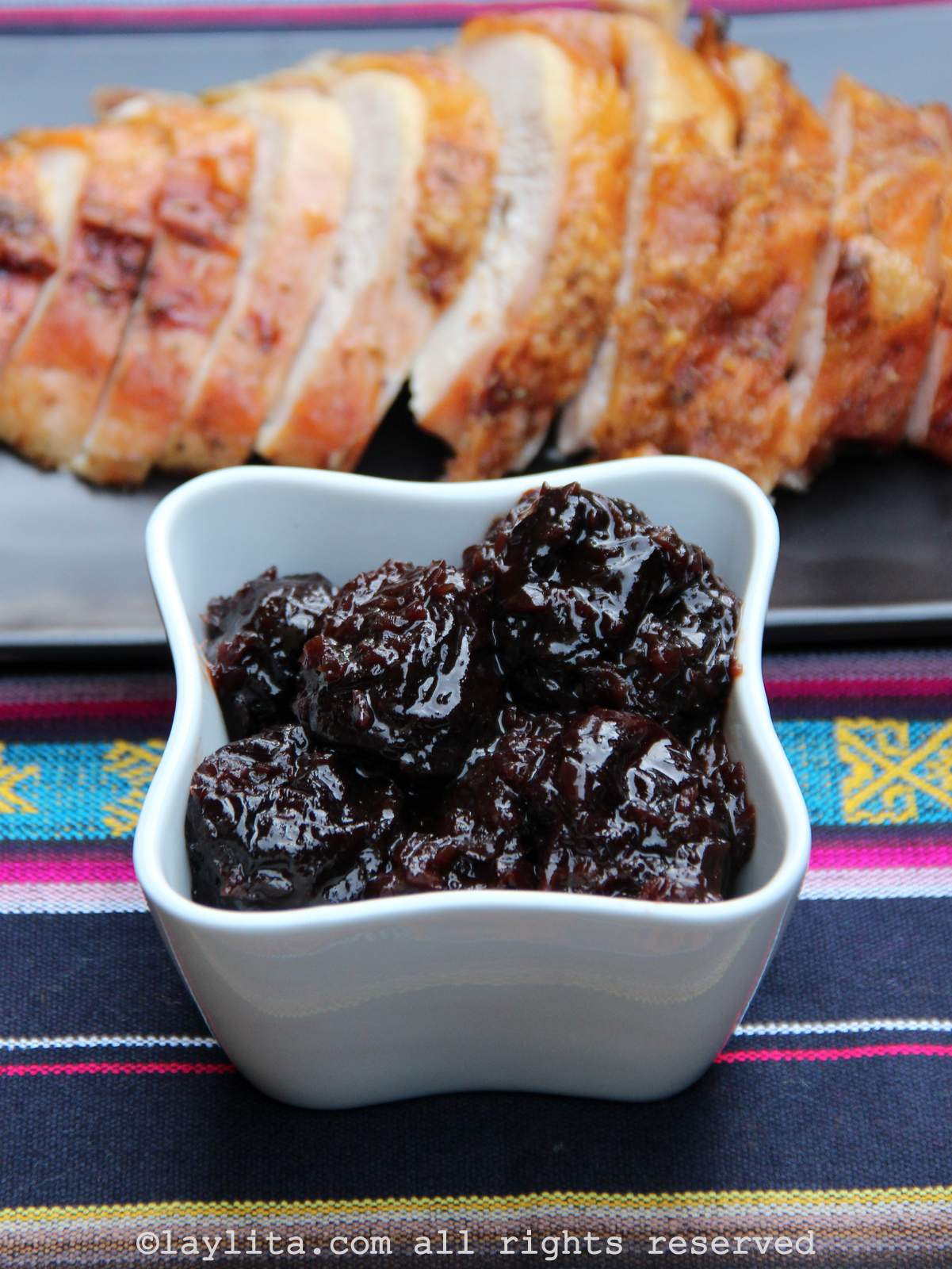 Un bol con salsa de ciruela y una pechuga de pavo asado en el fondo
