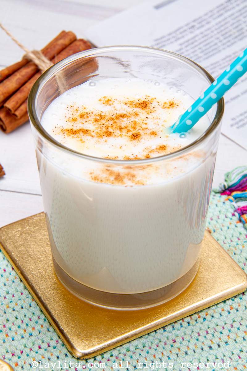 Chicha de arroz en un vaso de vidrio con canela espolovreada por encima y servida con un sorbete azúl