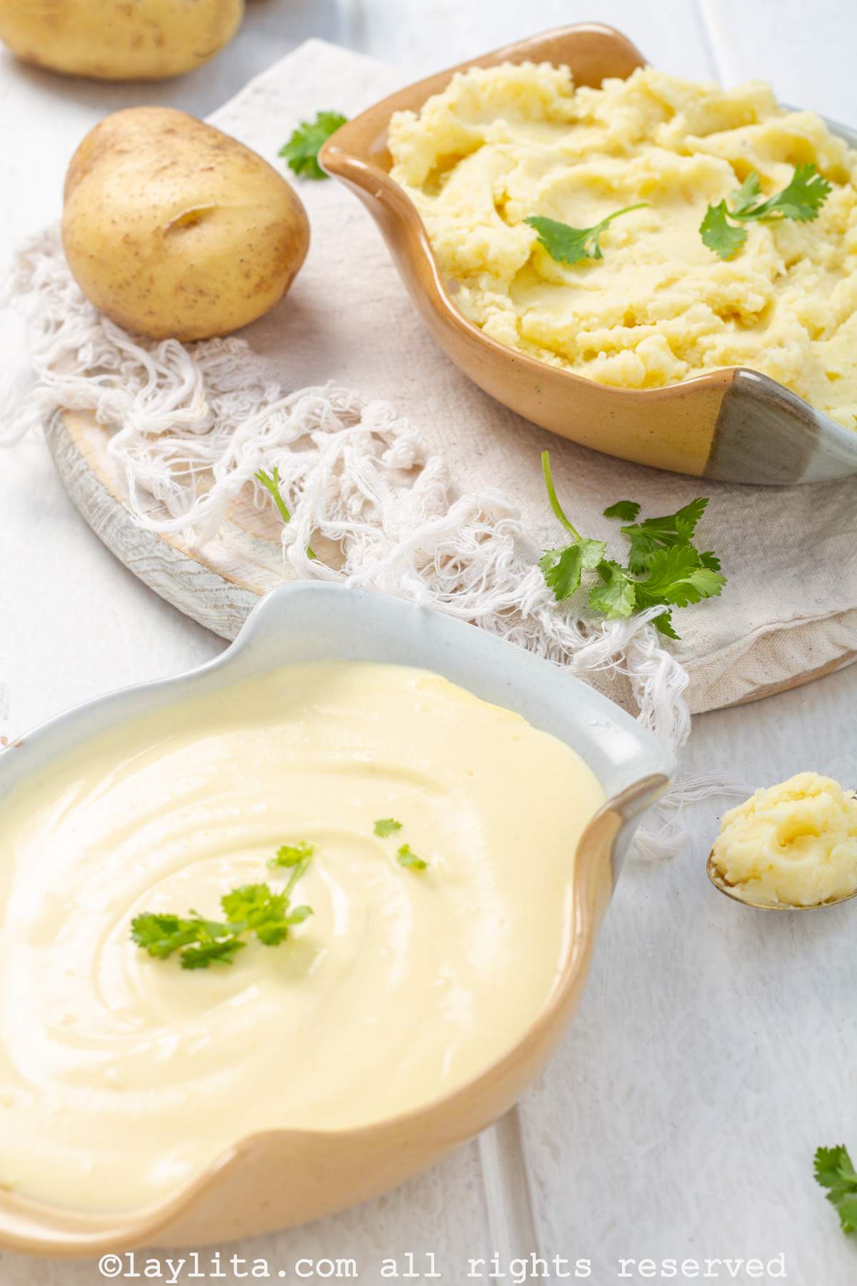 Dos recipientes llenos de pu´re de papas, el primero es una variación francesa cremosa y la de atrás es un puré casero rustico