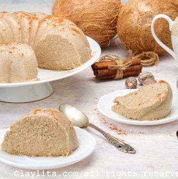 Rebanadas de majarete de coco en platos blancos con el resto en un servidor de pasteles al fondo