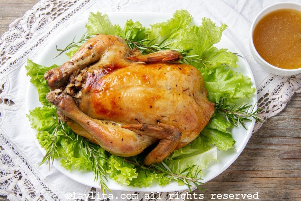 Pollo relleno asado encima de hojas de lechuga en una bandeja blanca