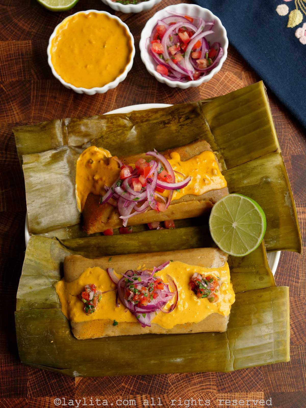 Bollos ecuatorianos de verde y pescado encima de hojas plátano con salsa de maní y curtido de cebolla