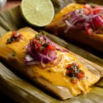 Un bollo de pescado ecuatoriano cubierto de salsa de maní (cacahuate) y curtido de cebolla