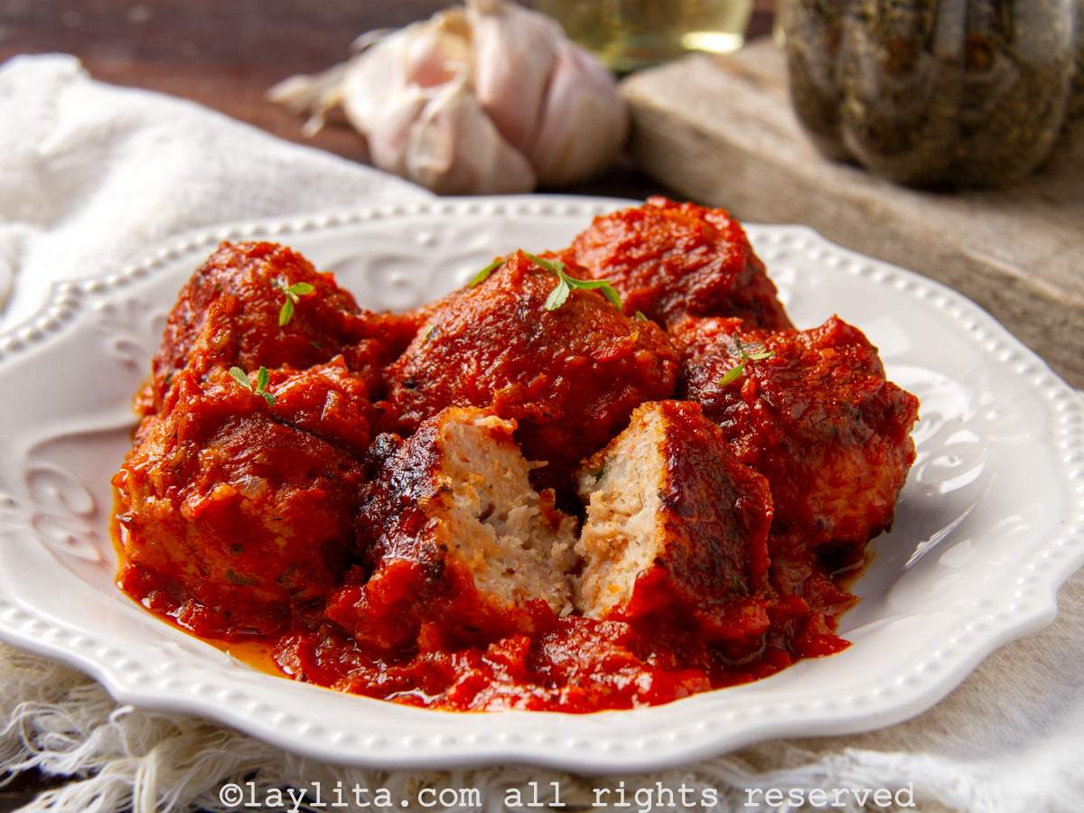 Un plato blanco con albóndigas de pollo en salsa de tomate