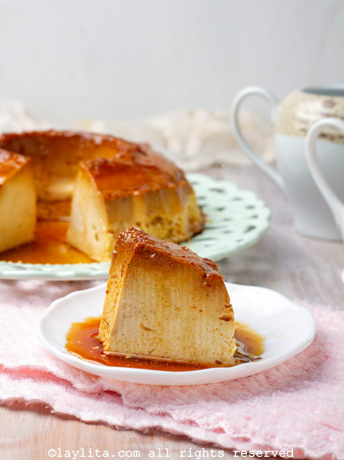Un pedazo de flan en un plato blanco, encima de una servilleta rosada
