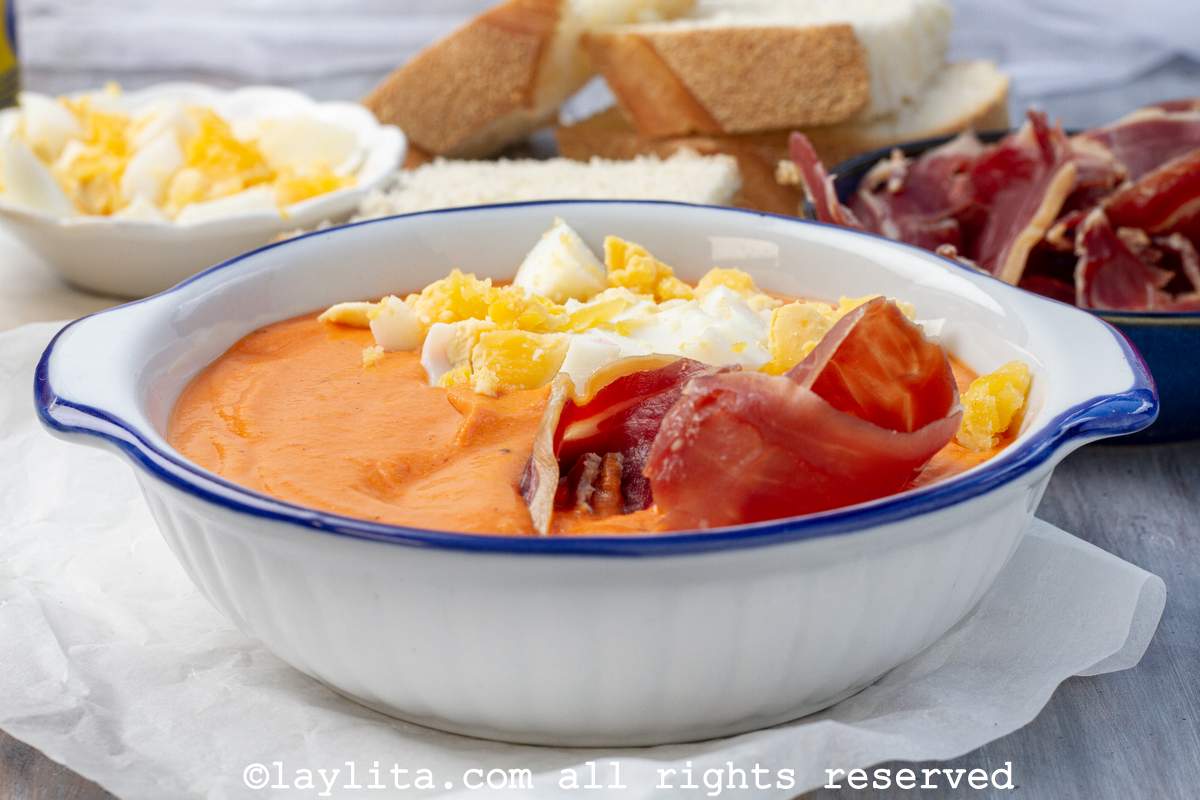 Salmorejo o sopa fría de tomates y pan en un bol, con huevos duros y jamón
