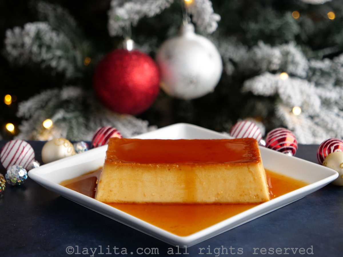 Flan de rompope en un plato blanco con un arbol de Navidad en el fondo