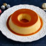 Flan de rompope en un plato blanco con decoraciones navideñas