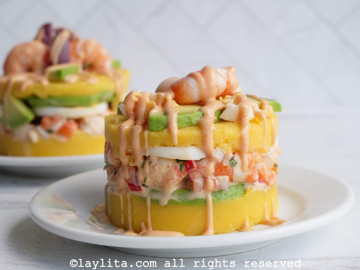 Causa de camarones en un plato blanco con otra causa en el fondo