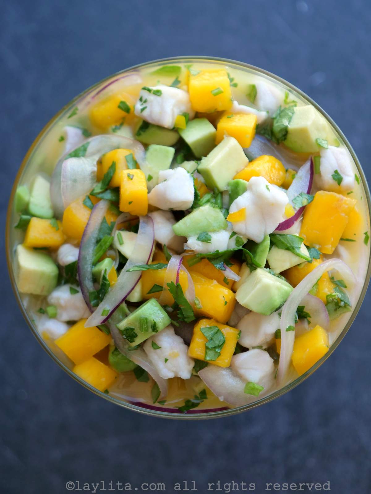 Ceviche de pecado con trozos de mango y aguacate servido en una copa de vidrio