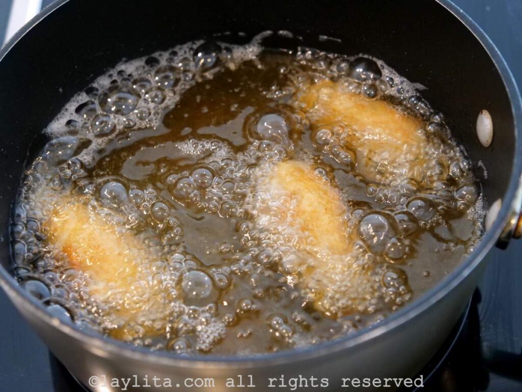 Tres croquetas de papa en una olla con aceite caliente