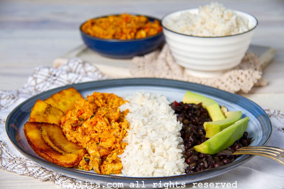 Un plato de pabellón de pescado con pisillo, arroz, caraotas, platano frito, y aguacate