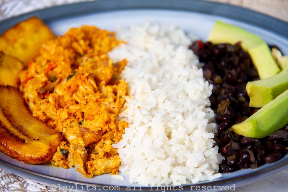 Platanos fritos, pisillo de cazon, arroz, caraotas negras, y aguacate en un plato