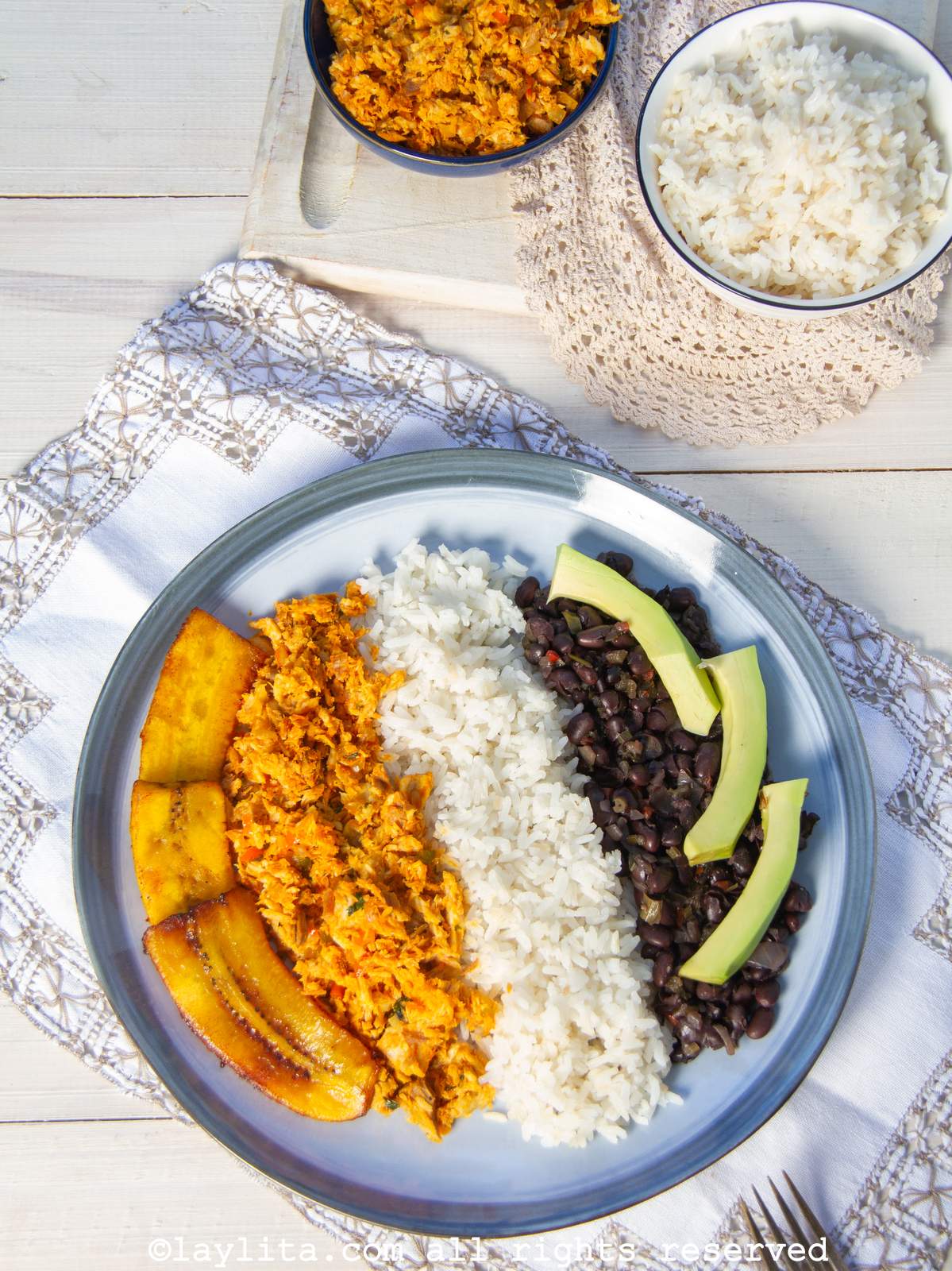 Un plato de pabellón de pescado con pisillo, arroz, caraotas, platano frito, y aguacate