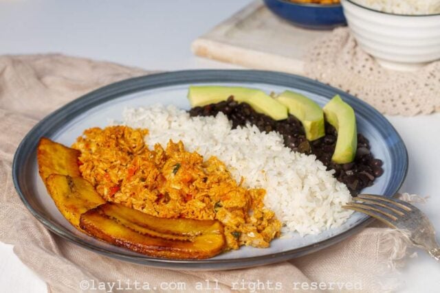 Platanos fritos, pisillo de cazon, arroz, caraotas negras, y aguacate en un plato