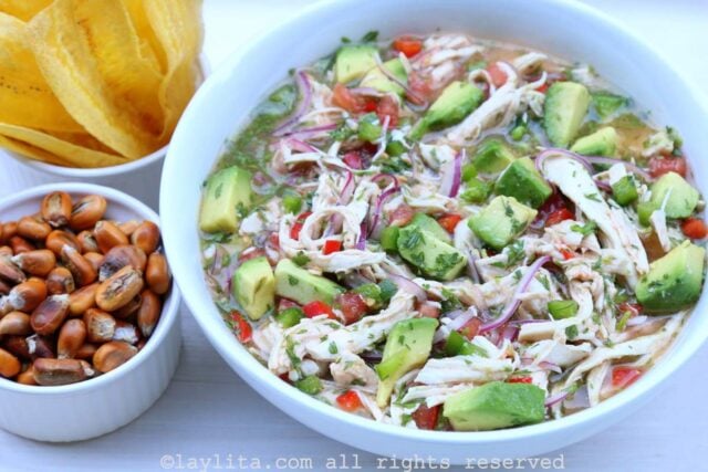 Un plato de ceviche de pollo y aguacate con chifles y maíz tostado al lado