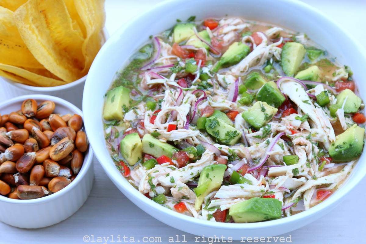 Un plato de ceviche de pollo y aguacate con chifles y maíz tostado al lado