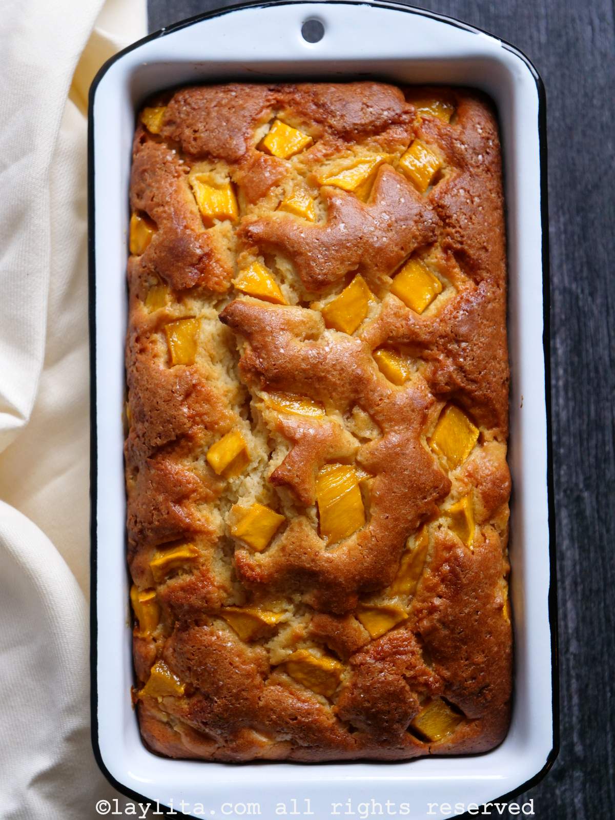 Bizcocho o torta de mango en un molde blanco con una servilleta de color crema al costado