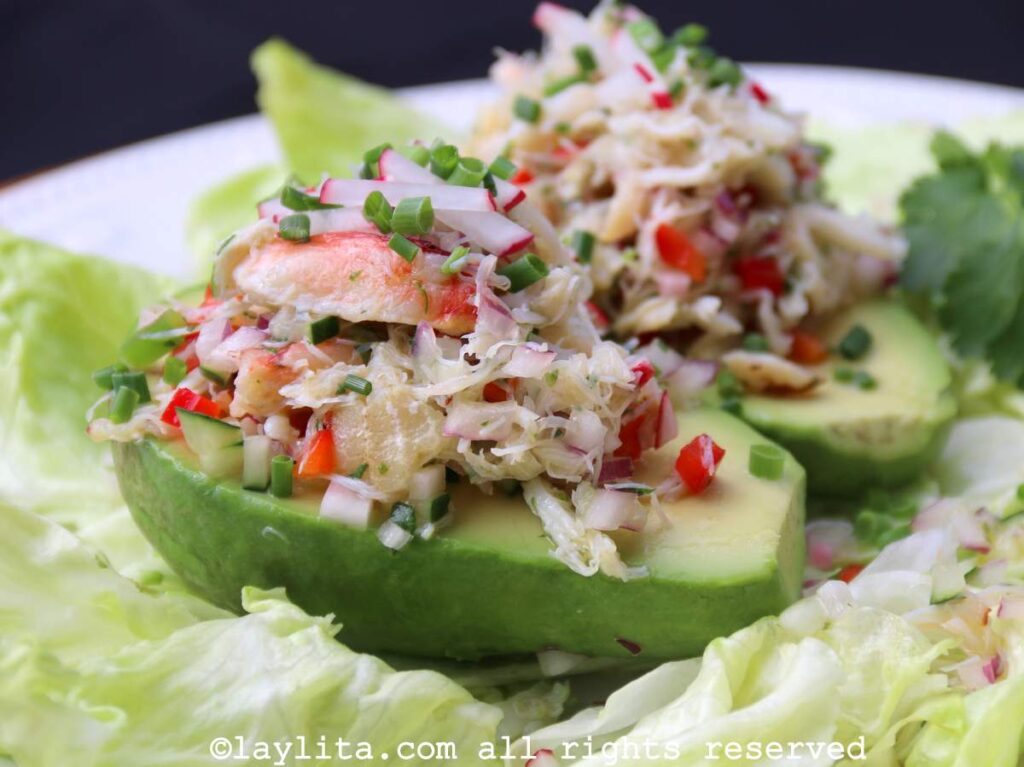 Dos mitades de aguacates rellenos con ensalada de cangrejo encima de hojas de lechuga