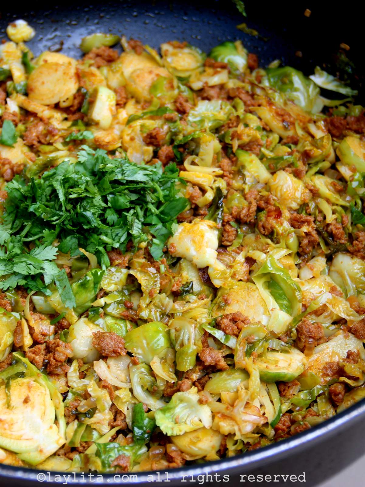 Una sartén llena de coles de Bruselas salteadas con chorizo y cilantro