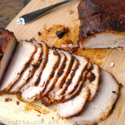Un lomo de cerdo asado cortado en rodajas finas en una tabla de picar