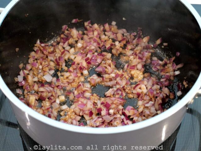 Cebolla morada picadito y ajo molido cocinandose en una olla