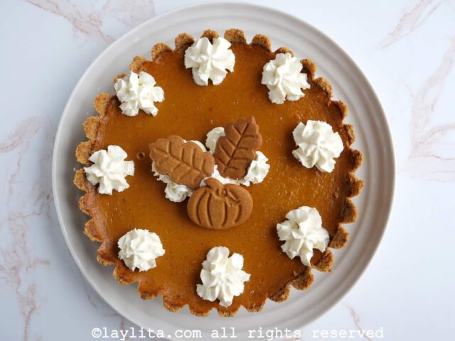 Pastel de calabaza decorado con crema chantilly y galletas en un plato blanco