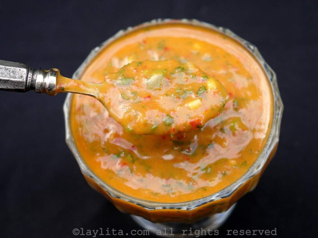 Un bol de vidrio lleno de ají o salsa picante de tomate de árbol con una cuchara
