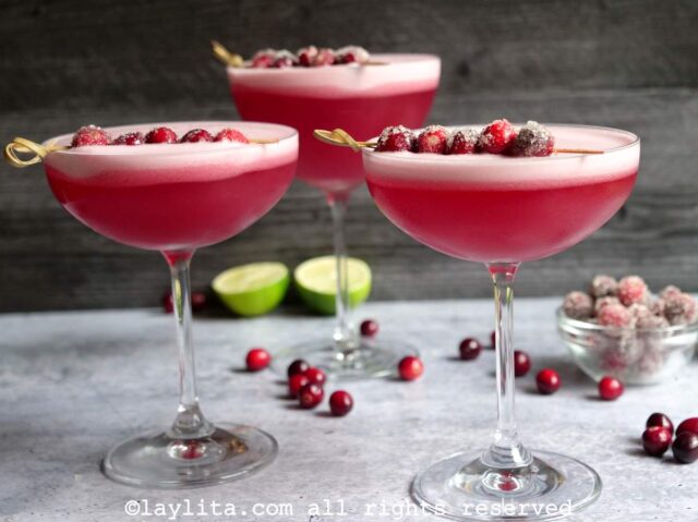Tres copas llenas de liquido rojizo espumoso y decorado con arándanos rojos
