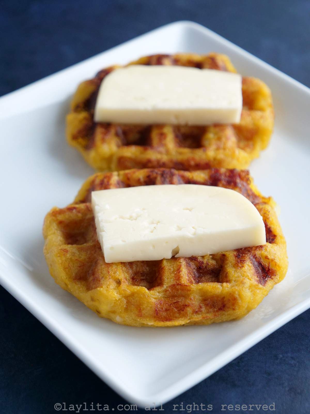 Dos waffles de plátano maduro con queso encima en un plato blanco