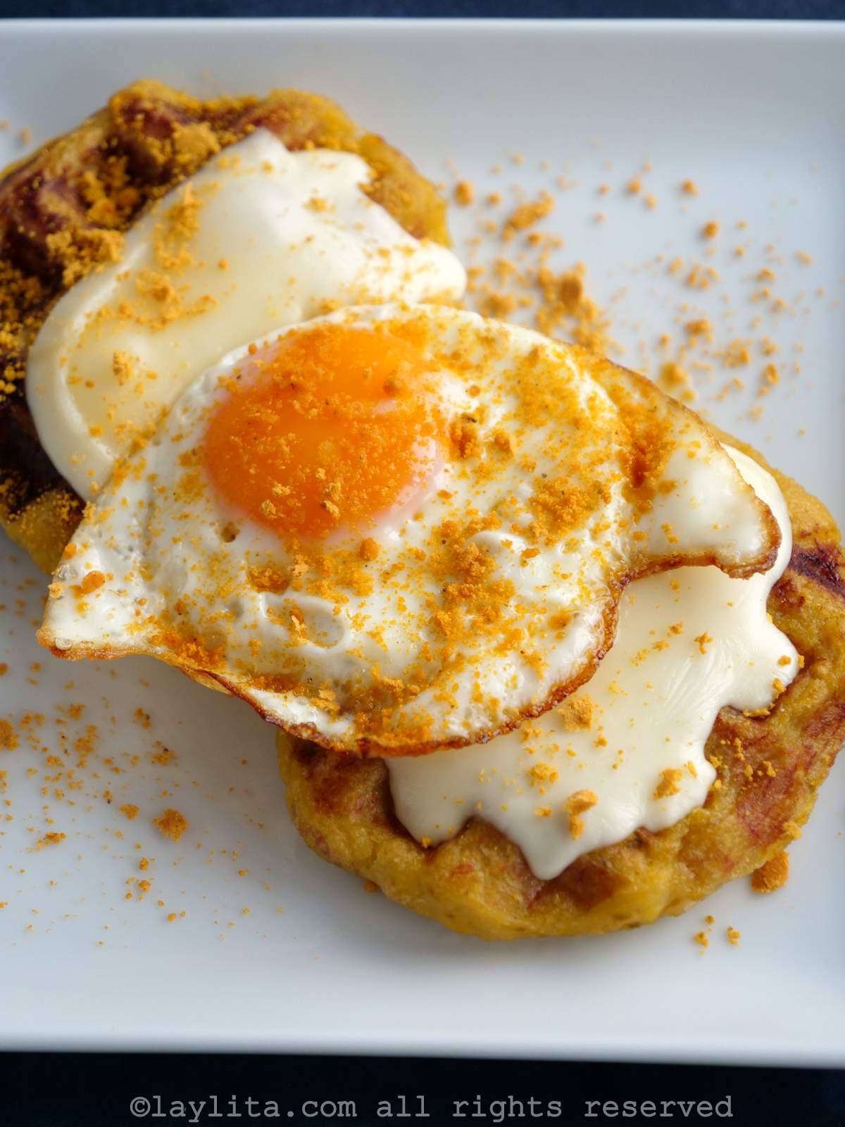 Dos waffles de plátano maduro con queso derretido y un huevo frito