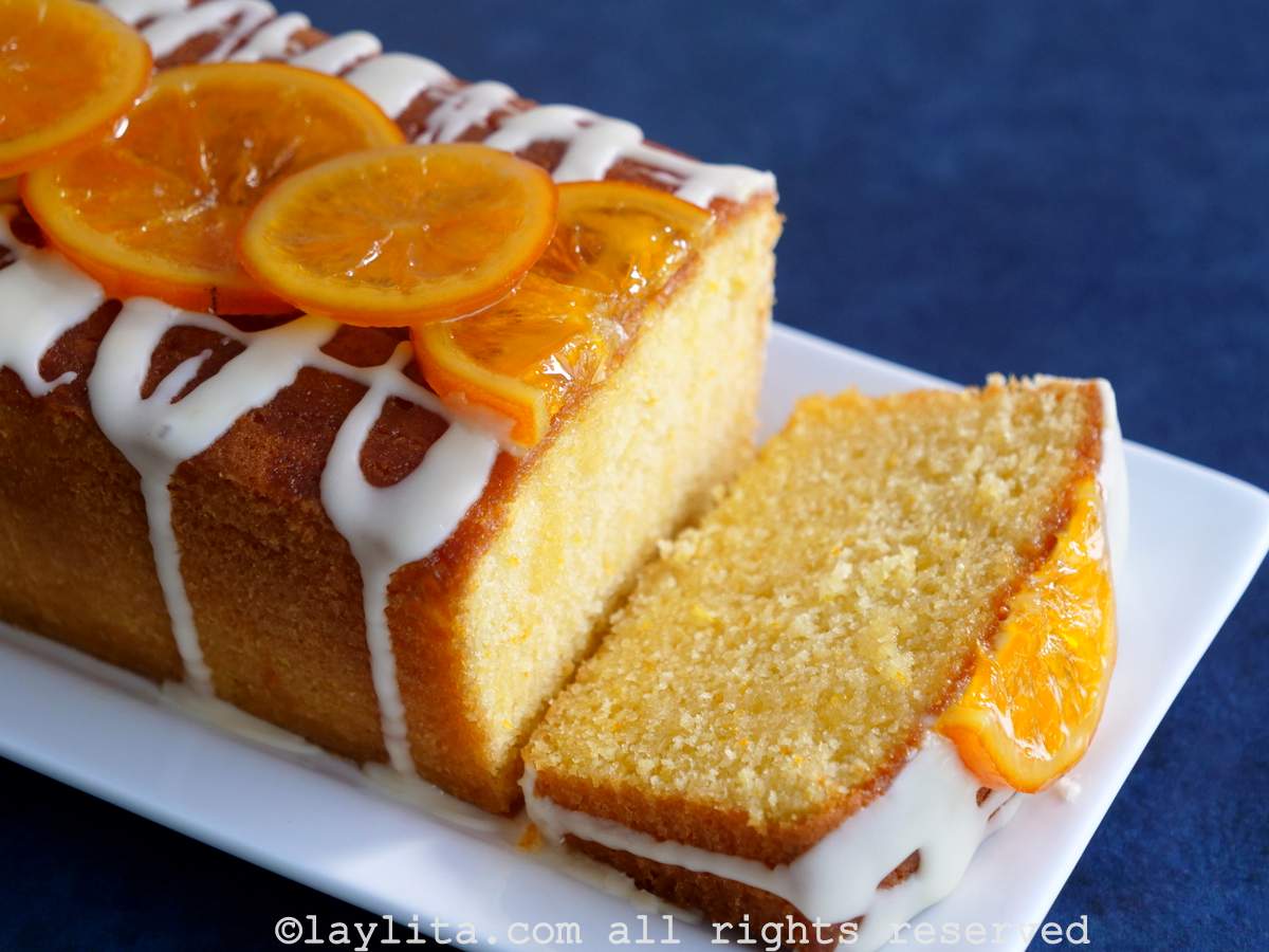 Un bizcocho de naranja con una rebanada cortada en un plato blanco