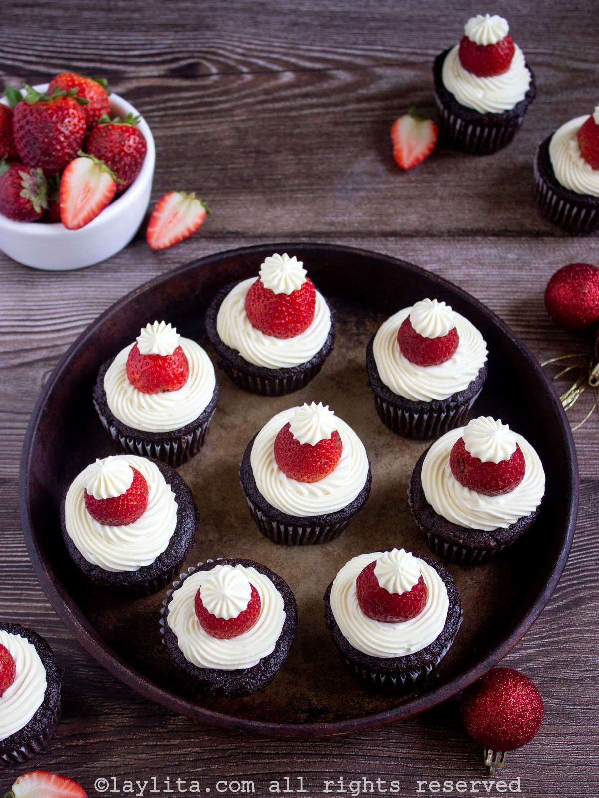 Una bandeja redonda llena de cupcakes navideños con decoración de Papá Noel