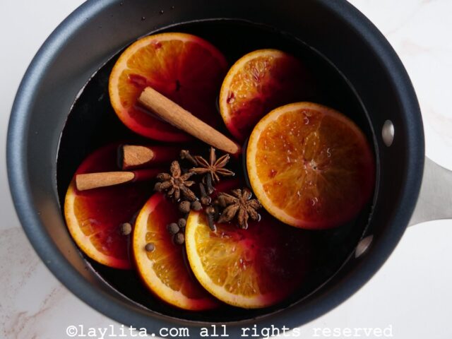 Rodajas de naranja, especias y vino tinto en una olla