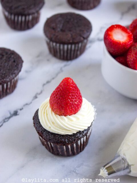 Un cupcake de chocolate decorado con cobertura blanca y una fresa