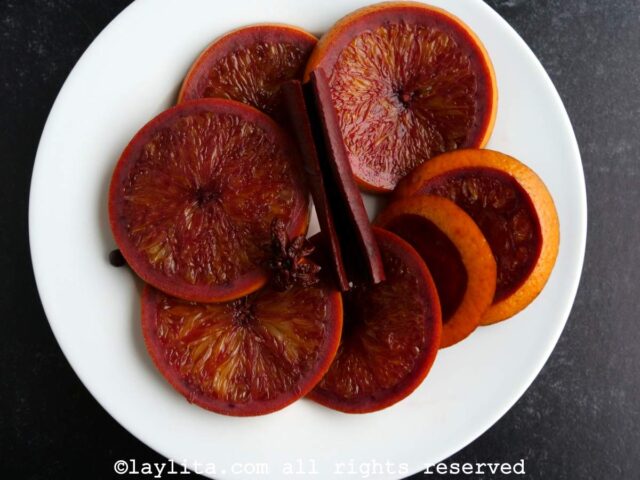 Rodajas de naranja y ramas de canela en un plato