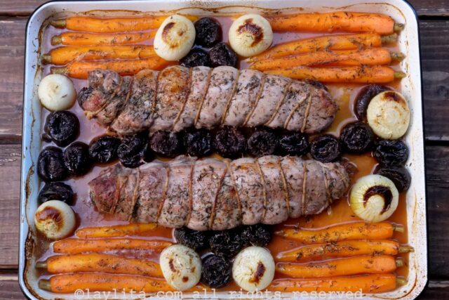 Una bandeja de hornear con zanahorias, cebollas, ciruelas pasas y solomillos de cerdo