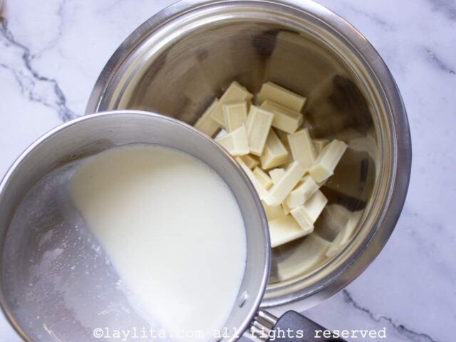 Agregando la crema de leche caliente al bol con los trozos de chocolate blanco