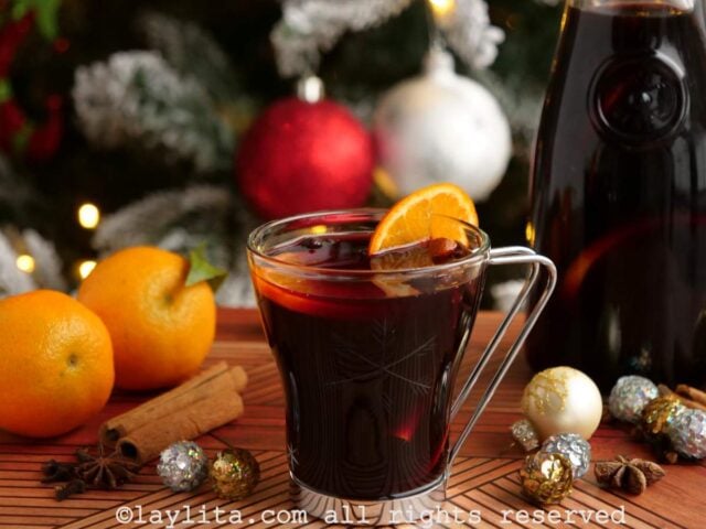 Un vaso de vidrio lleno de Vino Caliente con decoraciones navideñas en el fondo