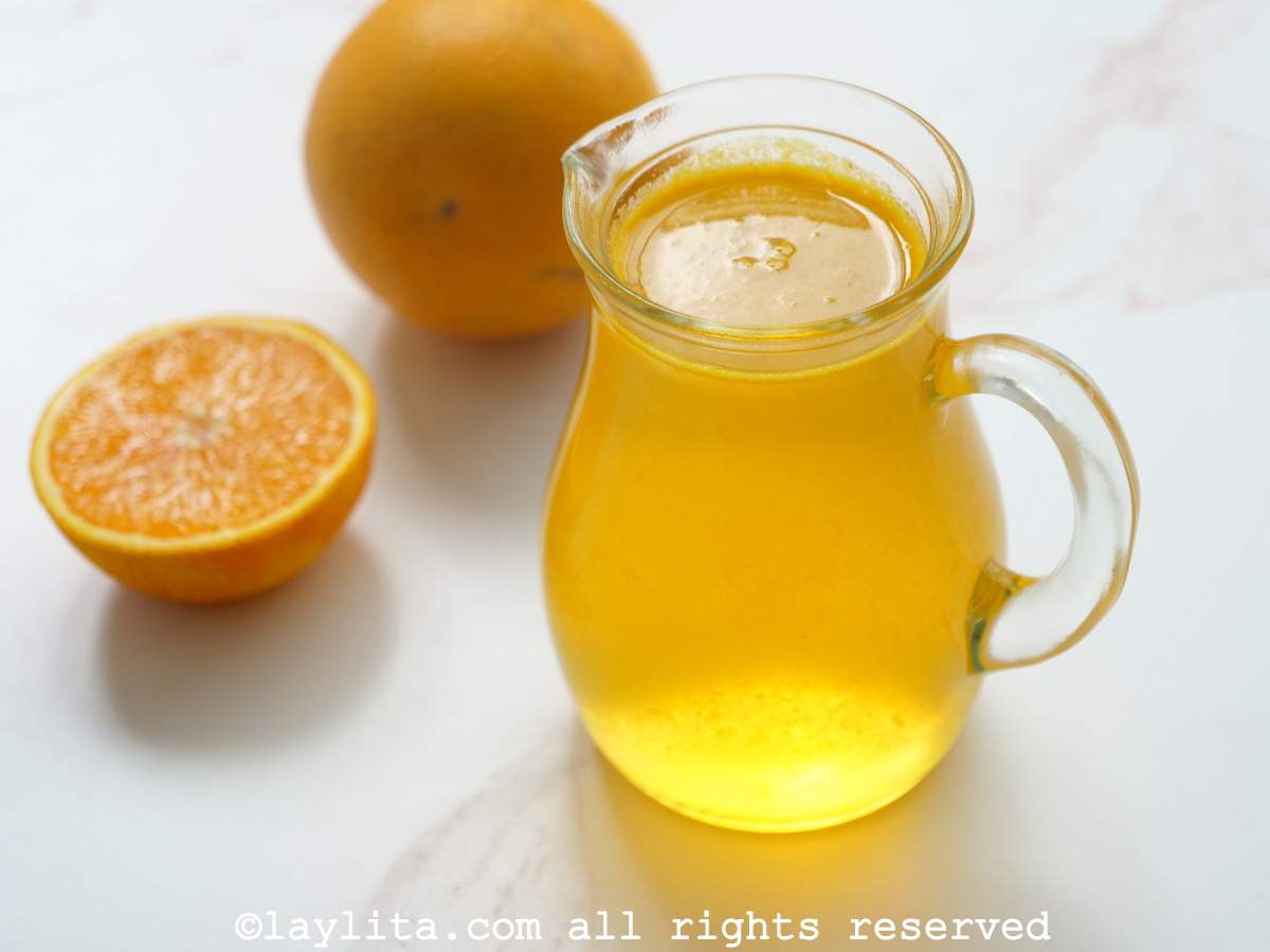 Una jarrita con almíbar de naranja y una media naranja al lado