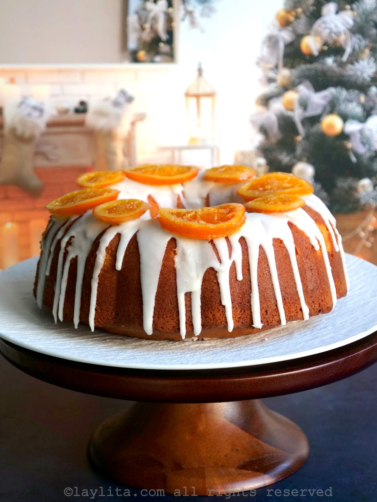 Un pastel de naranja en un plato blanco con un arbol navideño en el fondo